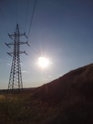 Prudké letní Slunce se kloní k západu mezi sloupem VVN a kopečkem chráněného území Člupy.