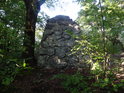 Kamenný pomník S. K. Neuman pohledem zezadu z lesa.