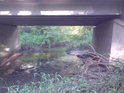 Pod silničním mostem musí nevolky protékat potok Hořina.