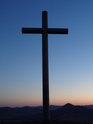 Ocelový kříž na vrcholu Radobýlu po západu Slunce, které ještě úžasně osvětluje homole Českého středohoří.